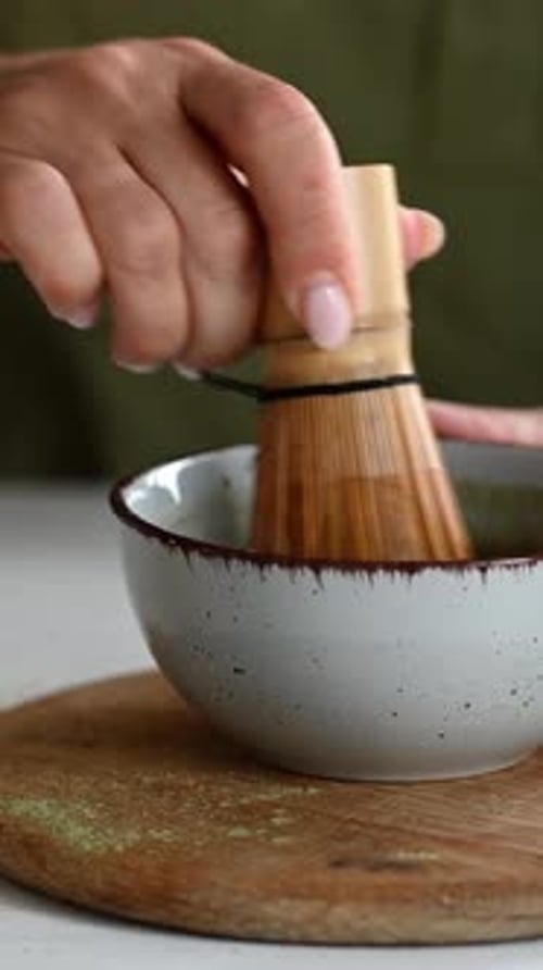 Woman Preparing Matcha Tea with Bamboo Whisk