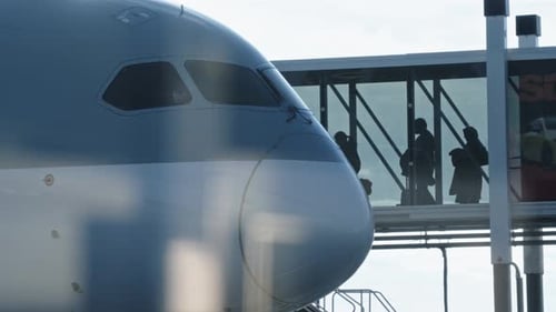 Passengers through departure gate at airport boarding plane via jet bridge, tele