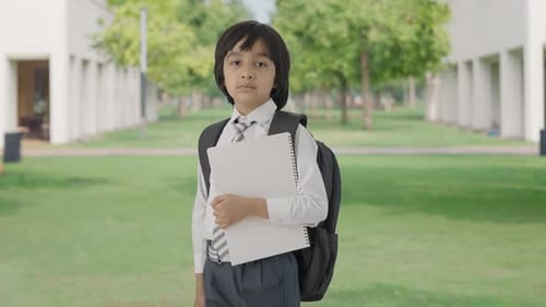 Portrait of Indian school boy standing with books