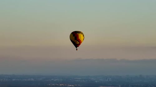 Hot Air Balloon Floating Over City at Sunset