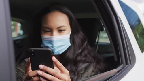 Young Woman Uses Phone in Car with Mask