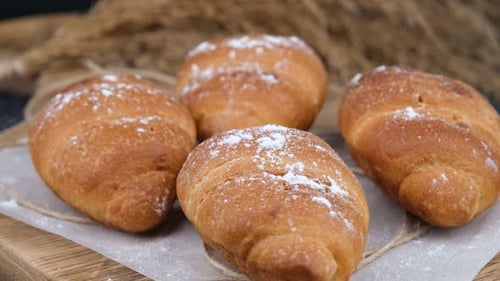 Croissants Sprinkled with Powdered Sugar on Wooden Board