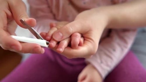 Parent Clipping a Child's Fingernails at Home