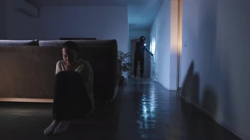 A mulher se escondeu atrás do sofá e está com medo