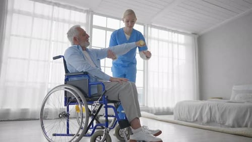 Senior Man in Wheelchair Exercises with Nurse