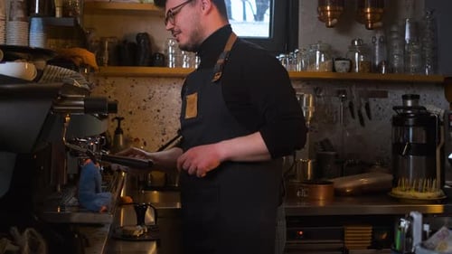 Barista working behind the counter in the cafe, getting ready to make coffee.
