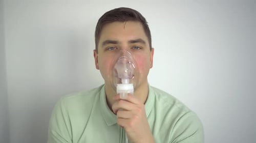 Un jeune homme respire à l'aide d'un inhalateur en gros plan Un homme portant un masque à oxygène est traité pour un
