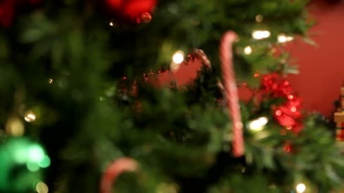 Girl decorating christmas tree with ornaments in home