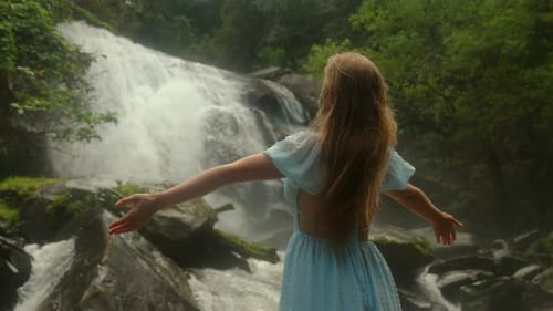 Woman in Blue Dress with Outstretched Arms Stands in Front of