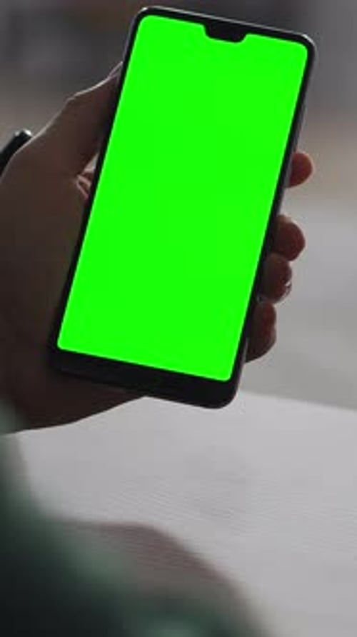 Closeup of Person Holding Modern Smartphone with Bright Green Chroma Key Screen Showcasing Blank