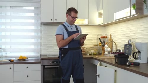Handyman Using Tablet Inspecting Kitchen with Toolbox