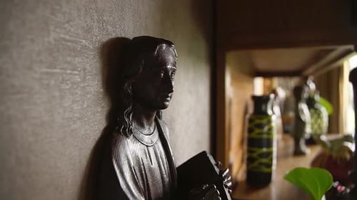 Nahaufnahme einer kleinen Innenstatue von Jesus Christus, der die Bibel in einem religiösen Haus hält.