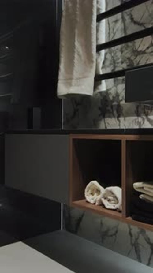 Vertical Screen Clean Towels Ready for Use Lie on a Shelf in a Modern Bathroom with Black Tones and