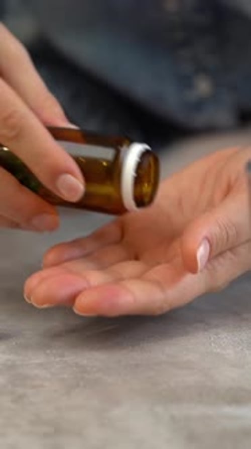 Woman Opens Pill Bottle and Pours Out Capsules