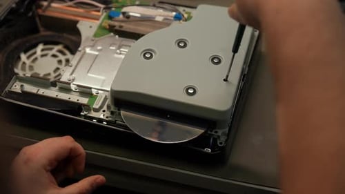 Closeup of Technician Hands Removing Disc From Game Console During Repair in Workshop Unscrewing