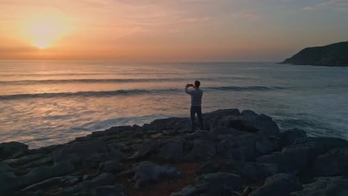 Tourist Man Taking Picture Sunset Ocean Marine Sea Waves Reflecting Bright Sun