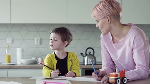 Woman and Child Drawing Together in Kitchen
