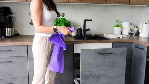 Mujer joven reemplaza la bolsa de basura en el bote de basura de la cocina, concepto de tareas domésticas