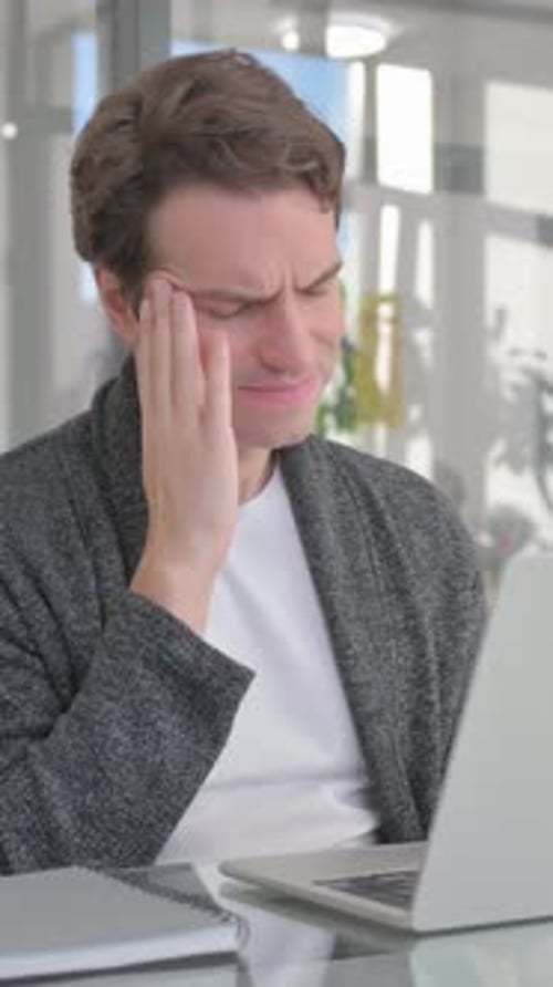 Man Massaging Temples at Desk With Computer Headache