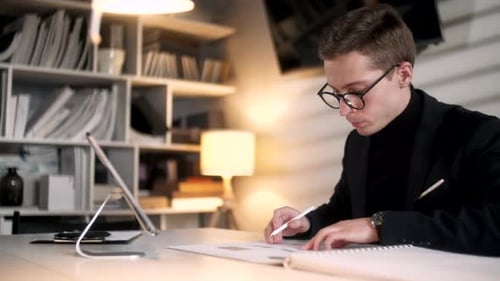 Geschäftsmann, Ingenieur arbeitet mit Bauplänen und Laptop an einem modernen Arbeitsplatz. Ein hübscher Mann ist