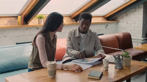Man Explaining Financial Data to Colleague in Loft Coworking Office