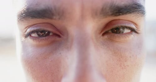 Portrait close up of eyes of happy biracial man looking at camera, slow motion