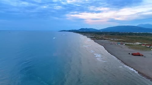 Seagulls fly over the vast blue tranquil waterscape of the Adriatic Sea at sunset.