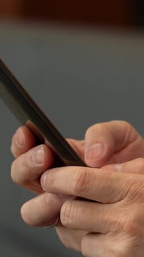 Close-up of man's hands using smartphone indoors