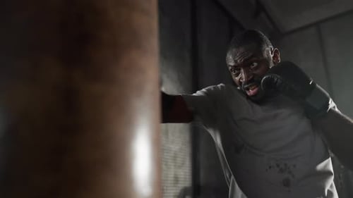 Boxer Training Hitting Punching Bag African American Sweated Sportsman Practicing Punches in Gym