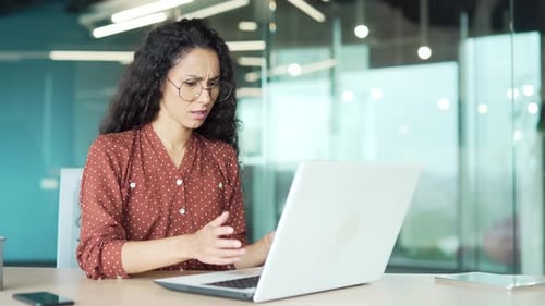 Worried Woman Working on Laptop in Modern Office