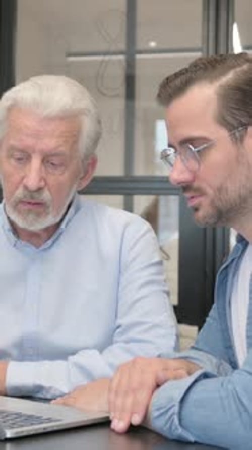 Two Men Collaborating Together Over a Laptop Indoors
