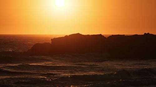 Waves crashing on rocks at the beach as the sun sets