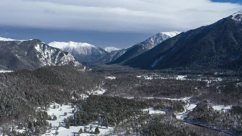 Air flight through mountain clouds over beautiful snow-capped peaks of mountains and glaciers.
