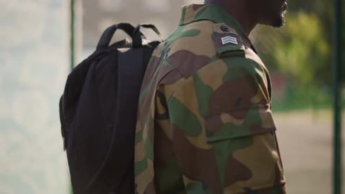 Threequarter View Soldier With Backpack Walking Along Fence Line Camo Sleeve Patch Steady Tempo Open