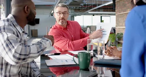 Team of diverse colleagues discussing over a document at office
