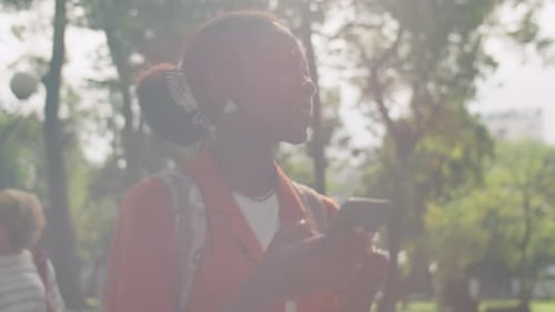 Black College Girl Walking in Park and Using Phone