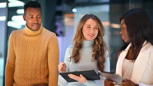 Multiracial group of workers walking in an office and discussing business affairs using tablets. Slo