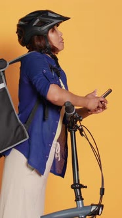 Woman Uses Smartphone Next to Folding Bicycle