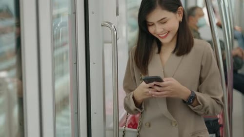A young beautiful businesswoman is using smart phone on Metro train