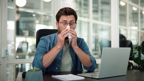 Unhealthy Male Employee Worker Sneezing While Working in Workplace in Office