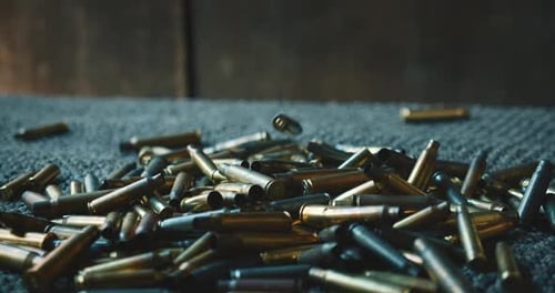 Beim Auswurf auf dem Schießstand fallen verbrauchte Patronenhülsen nacheinander auf einen Teppich