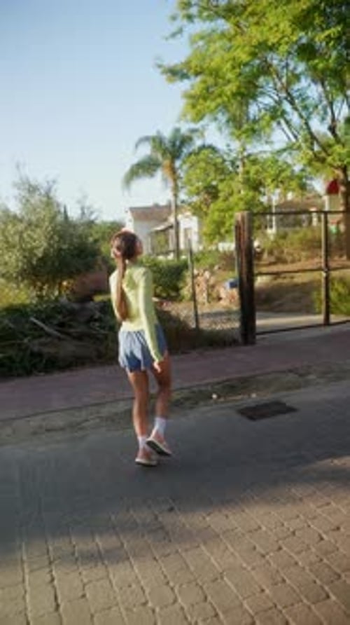A Young Woman is Exercising Outdoors in Sportswear Listening to Music with Headphones