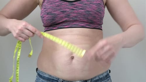 Woman Hands Holding Excessive Fat Belly with Measuring Tape on Gray Background