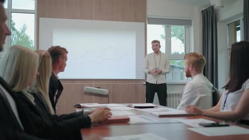 Männlicher IT-Spezialist präsentiert seinen Bericht im Treffen mit Kollegen im Konferenzsaal