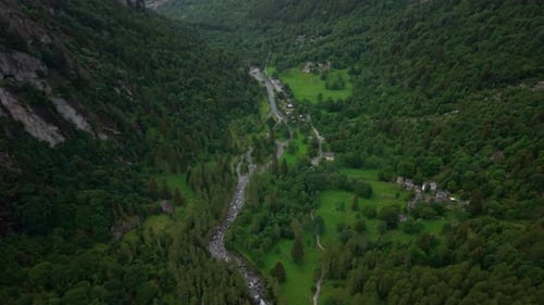 Aerial Forward Shot of a Green Valley with River and Mountains in the Alps