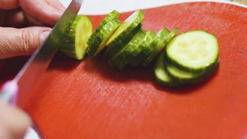 Cucumber Being Sliced on a Cutting Board