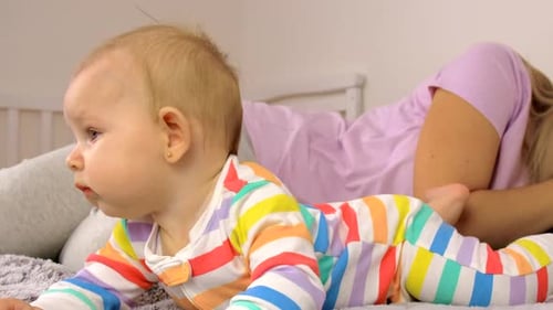 Baby Crawls on Bed Beside Sleeping Adult