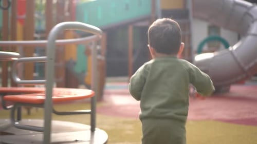 A Twoyearold Child Walks on a Playground Among Slides and Swings Little Son in the Park