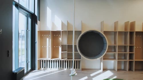 Photo de Dolly montrant une salle de jeux vide à l'intérieur : une corde accrochée au plafond, une grande étagère circulaire et bien d'autres