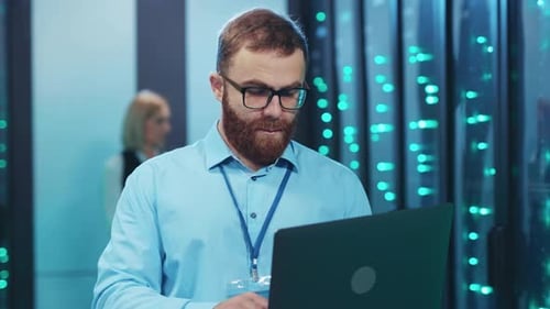 Technician Working on Laptop in Server Room